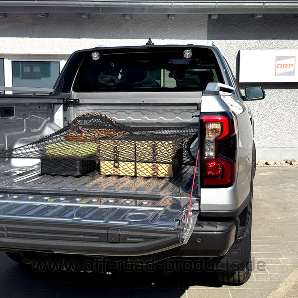 Auf dem Bild zu sehen ist ein Ford Ranger mit offener Ladefläche auf welchem mehrere Pakete und ein Korb auf der Ladefläche stehen. Die Pakete und der Korb sind mit einem Netz gesichert. Im Hintergrund sieht man eine Hauswand mit einem Schild auf der rechten Seite. Auf dem Schild ist ein Logo mit dem Schriftzug ORP.